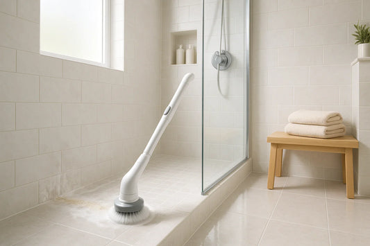 Electric spin scrubber cleaning soap scum from grout in a modern shower with pale gray tile
